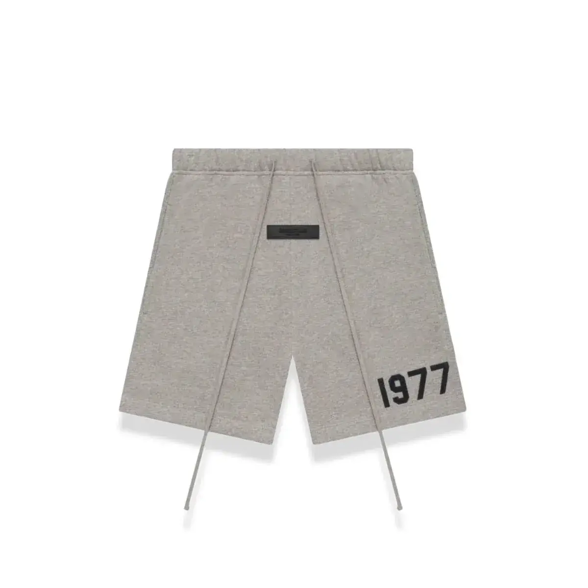 Light grey shorts with a minimalist design featuring a small black patch and bold "1977" print, part of the Fear of God Essentials 1977 Dark Oatmeal Summer Set, perfect casual wear.